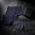 Premium branded men's boxer shorts in navy blue and charcoal grey on dark marble surface